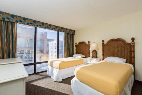 A hotel room with two twin beds, a desk, and a large window.
