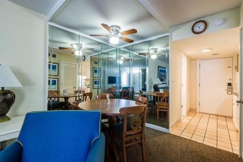 A dining area with a table and chairs, a blue chair, a mirror, and a ceiling fan.