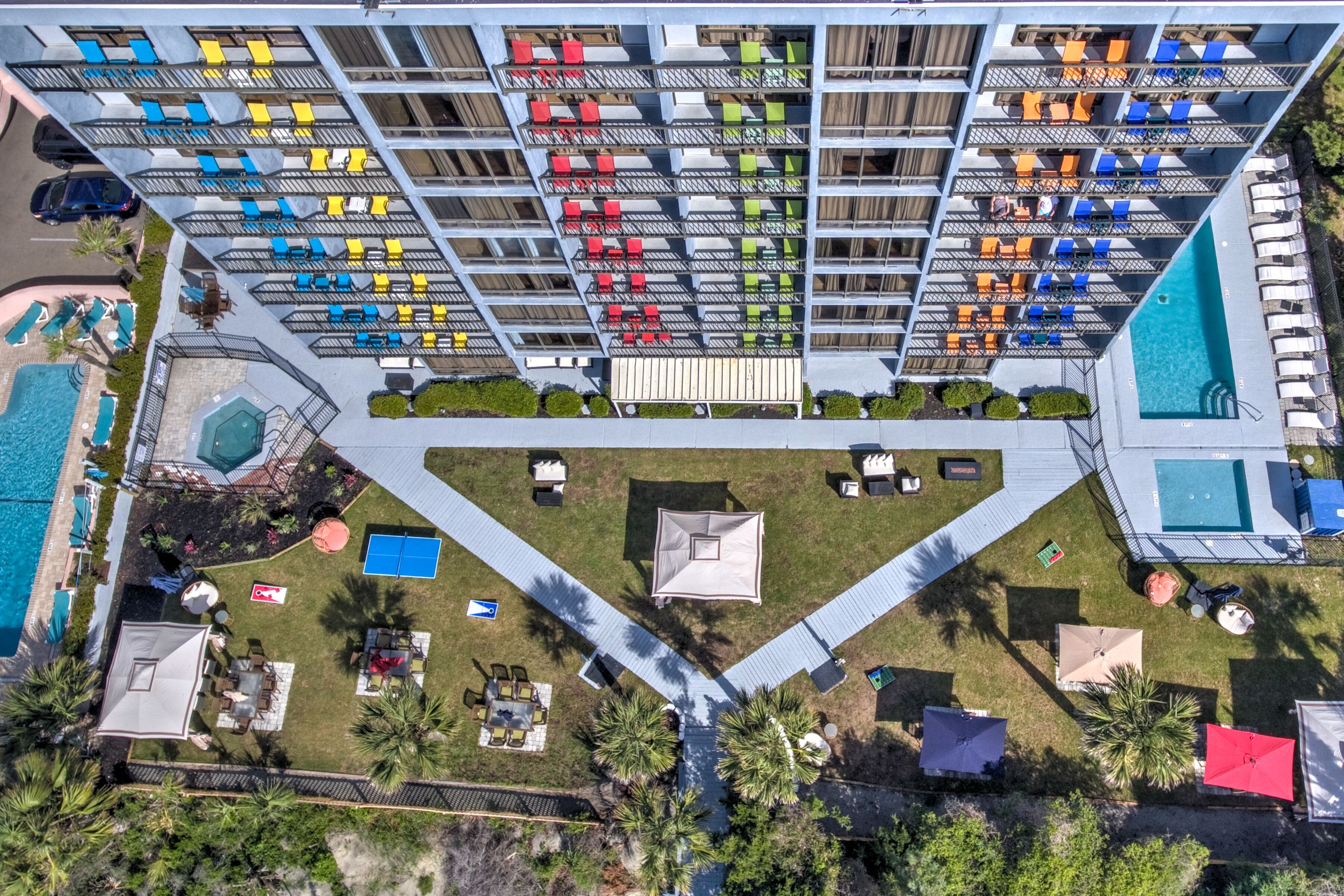 Aerial view of a large hotel complex with pools, umbrellas, and grass areas.